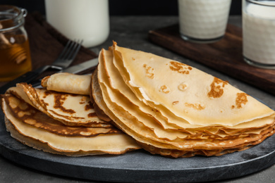 Photo of Fresh thin pancakes on grey board, closeup