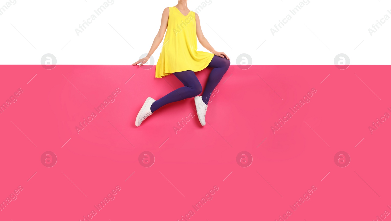 Photo of Woman wearing purple tights and stylish shoes sitting on color background, closeup