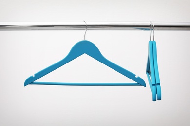 Photo of Clothes hangers on metal rail against light background