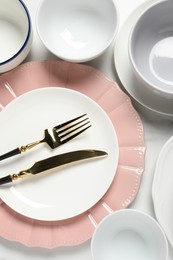 Beautiful ceramic dishware and cutlery on white table, flat lay