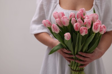 Photo of Woman with bouquet of beautiful fresh tulips on light grey background, closeup. Space for text