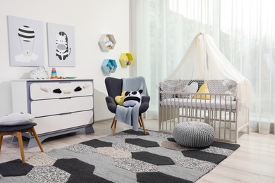 Photo of Cozy baby room with crib and other furniture. Interior design