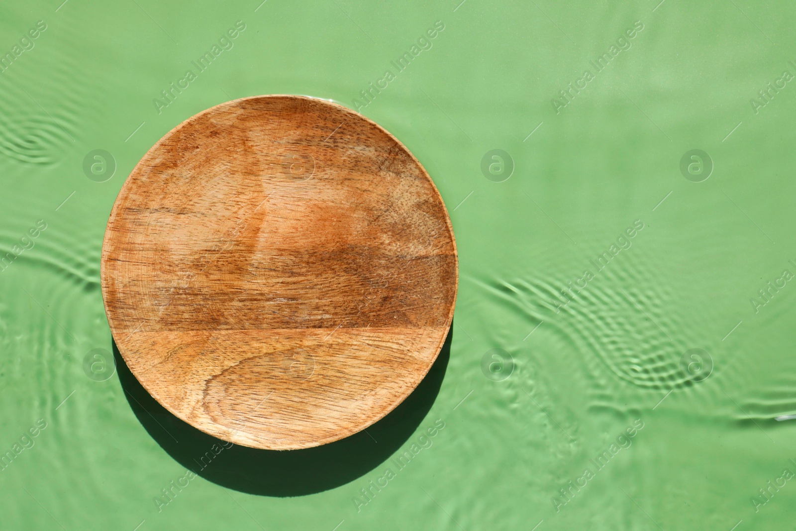 Photo of Presentation of product. Wooden podium in water on green background, top view. Space for text