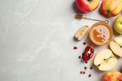 Photo of Flat lay composition with jar of honey, apples and pomegranate on marble background. Rosh Hashanah holiday