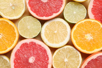 Different cut citrus fruits on beige table, flat lay