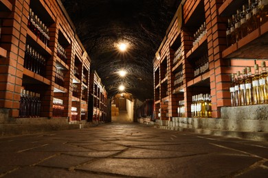Photo of Beregove, Ukraine - June 23, 2023: Many bottles of alcohol drinks on shelves in cellar, low angle view
