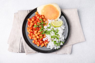 Photo of Delicious chickpea curry with rice and flatbread on light gray table, flat lay