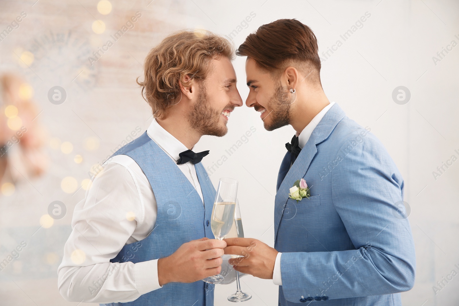 Photo of Happy newlywed gay couple with glasses of champagne at home