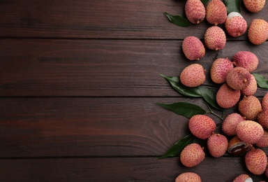 Fresh ripe lychee fruits on wooden table, flat lay. Space for text
