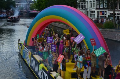 Photo of AMSTERDAM, NETHERLANDS - AUGUST 06, 2022: Many people in boat at LGBT pride parade on river