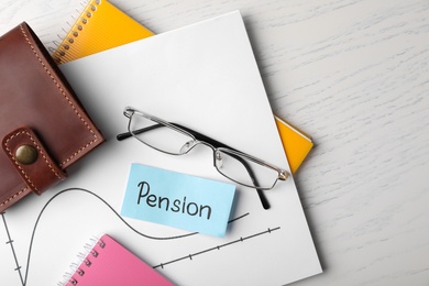 Photo of Paper with word PENSION, chart, glasses, wallet and notebooks on wooden background, top view