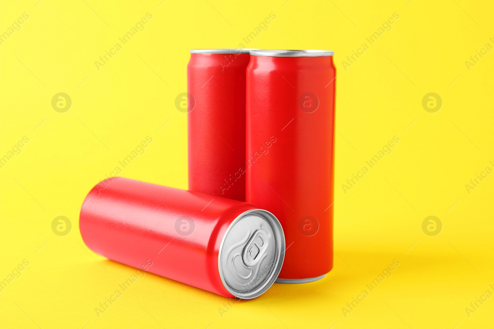 Photo of Energy drinks in red cans on yellow background