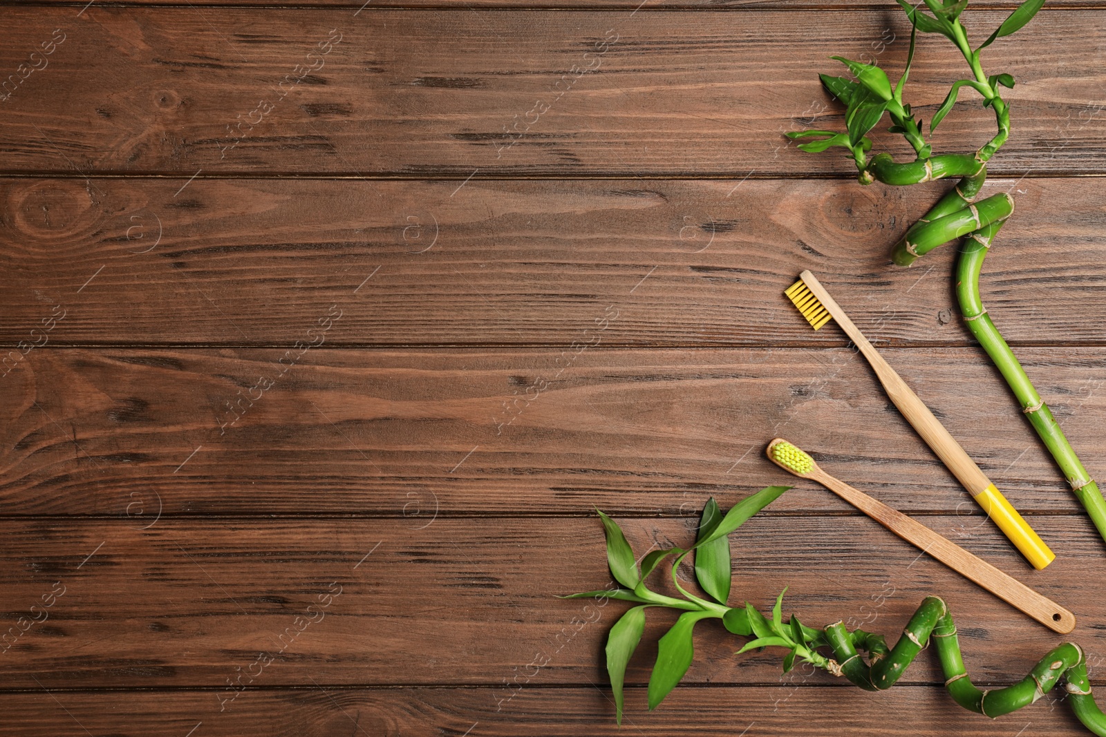 Photo of Flat lay composition with bamboo toothbrushes and space for text on wooden background