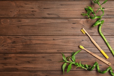 Photo of Flat lay composition with bamboo toothbrushes and space for text on wooden background