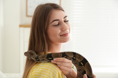 Photo of Young woman with boa constrictor at home. Exotic pet