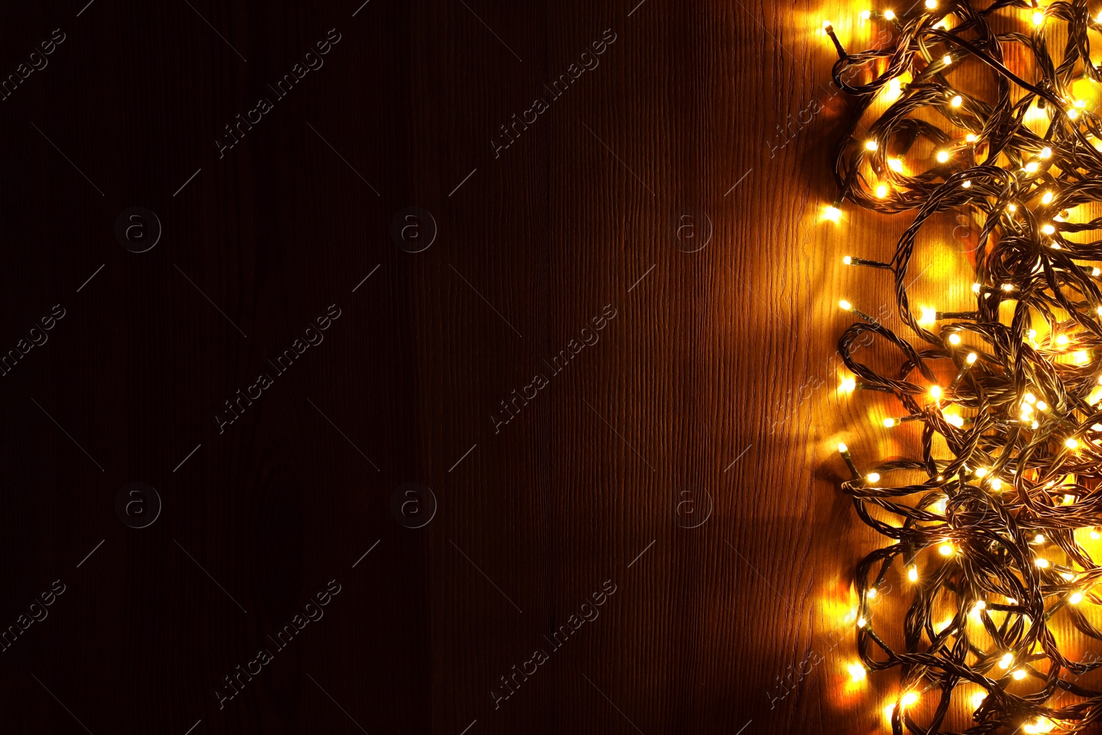 Photo of Beautiful bright Christmas lights on wooden background, flat lay. Space for text