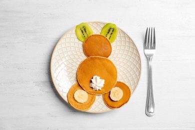 Photo of Funny pancakes for kids breakfast on wooden table, top view