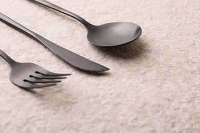 Stylish cutlery set on beige textured table, closeup. Space for text