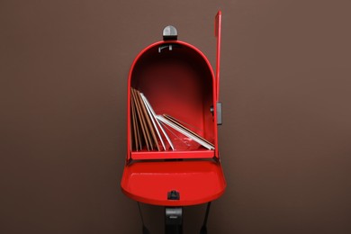 Photo of Open red letter box with envelopes against brown background