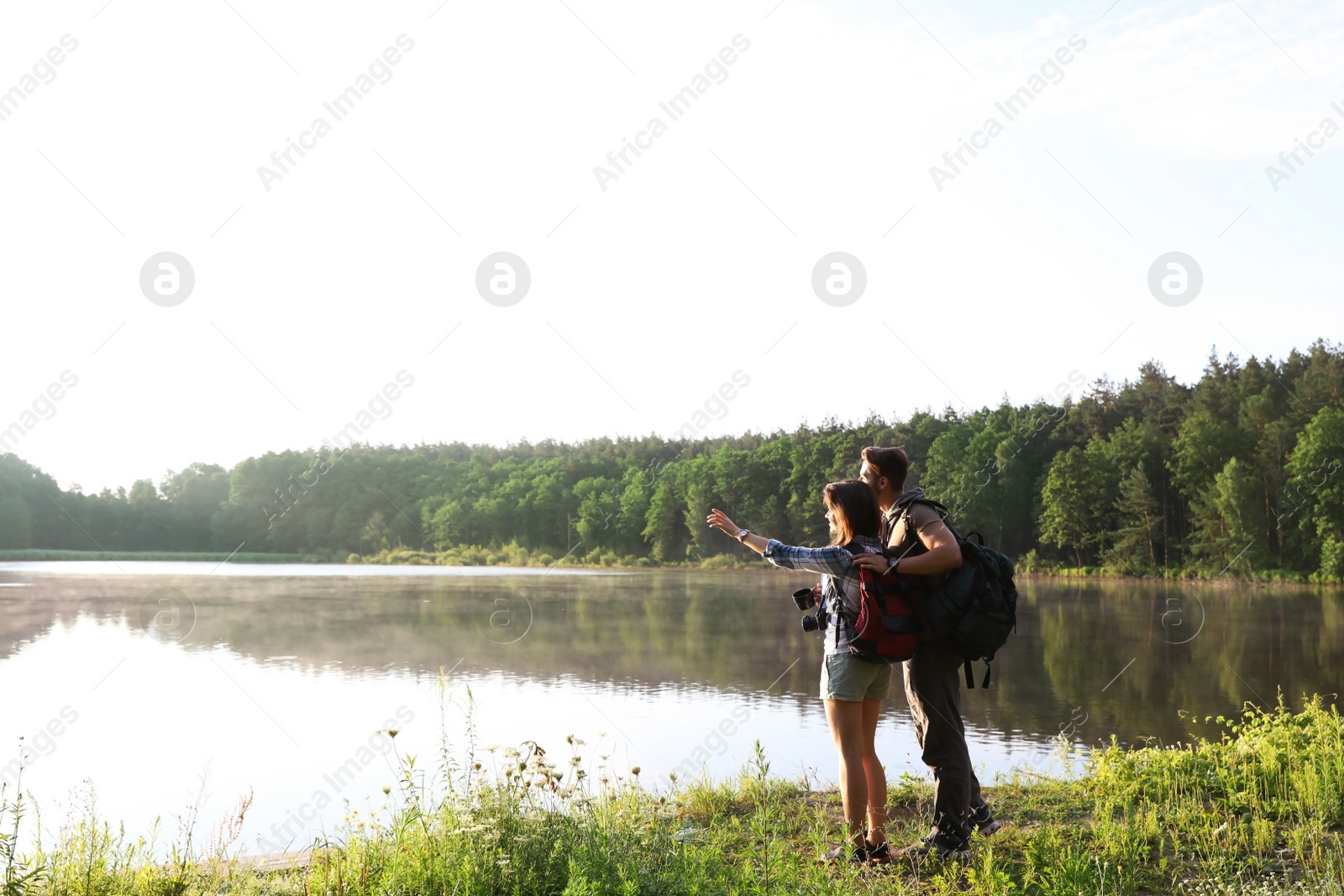 Photo of Young couple on shore of beautiful lake. Camping season