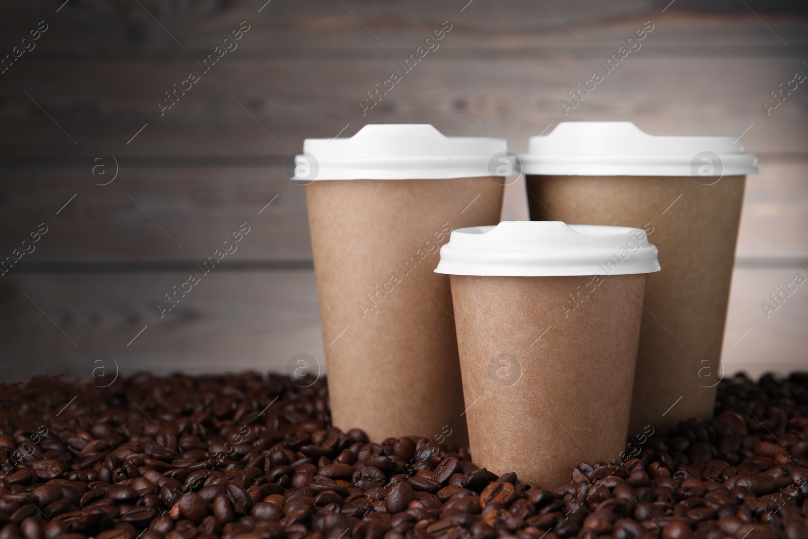 Photo of Coffee to go. Paper cups on roasted beans. Space for text