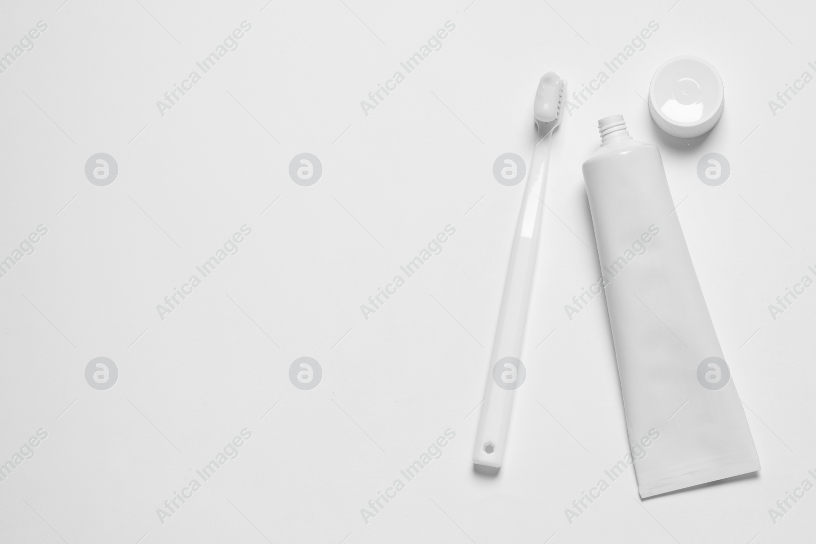 Photo of Plastic toothbrush and paste on white background, top view. Space for text