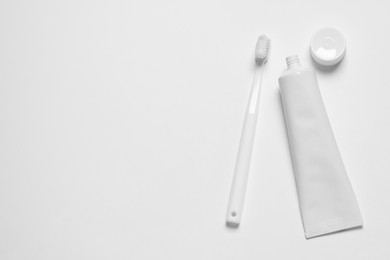 Photo of Plastic toothbrush and paste on white background, top view. Space for text