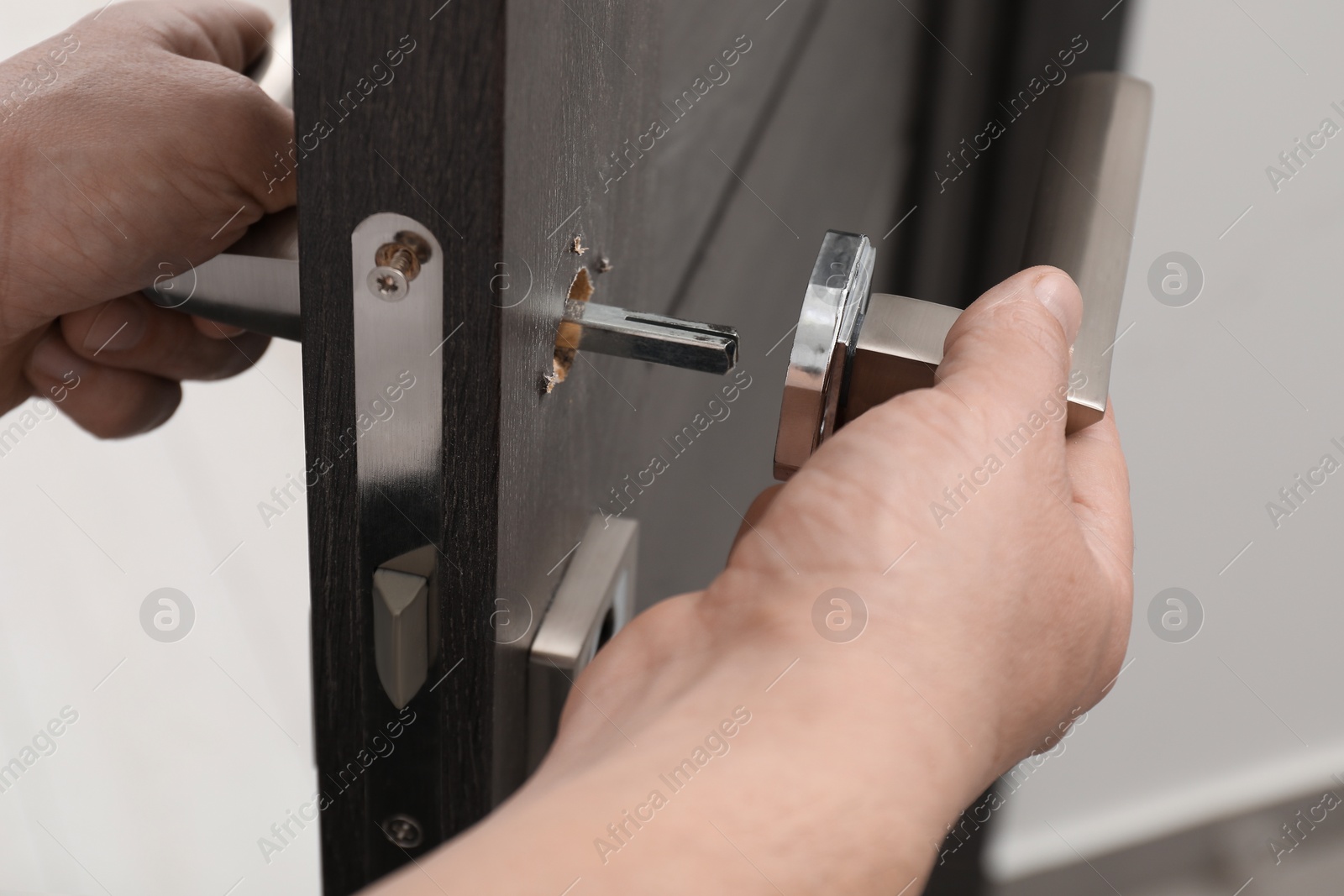 Photo of Handyman repairing door handle indoors, closeup view