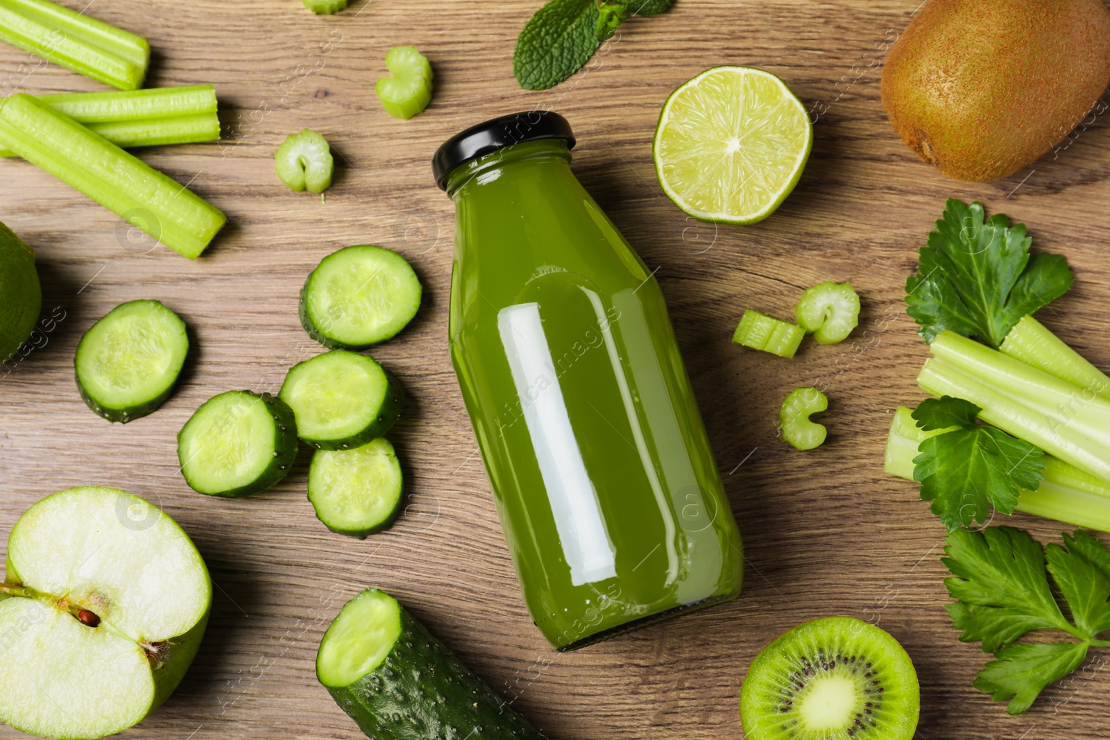 Photo of Glass bottle of celery juice and fresh ingredients on wooden table, flat lay