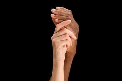 Woman and African American man holding hands on black background, closeup