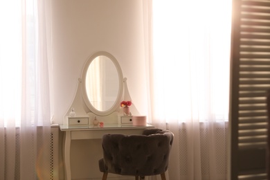 Elegant white dressing table and armchair in light room