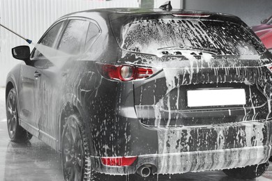 Washing auto with high pressure water jet at outdoor car wash