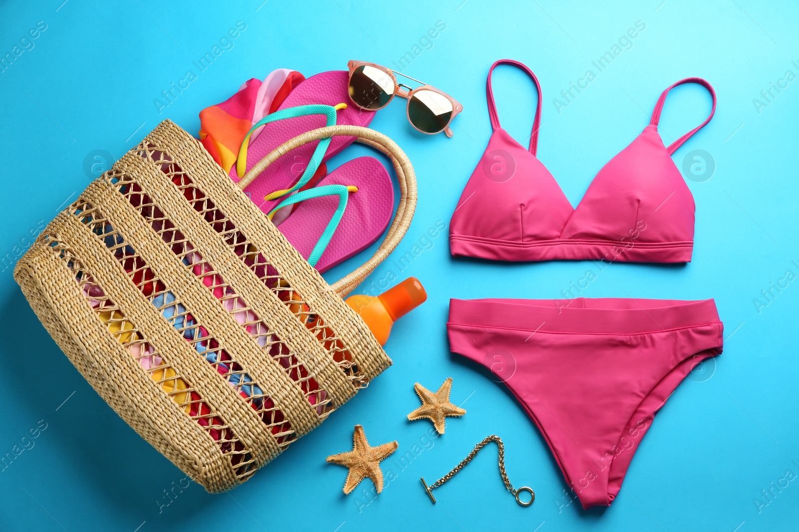 Photo of Beautiful pink bikini and beach accessories on light blue background, flat lay