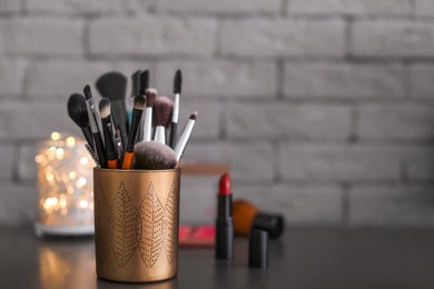 Holder with makeup brushes on table