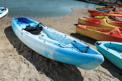 Many colorful kayaks on sand near sea