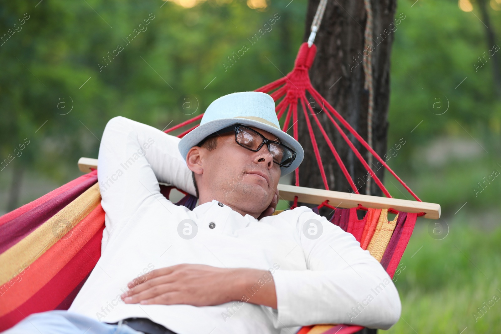 Photo of Man resting in comfortable hammock at green garden