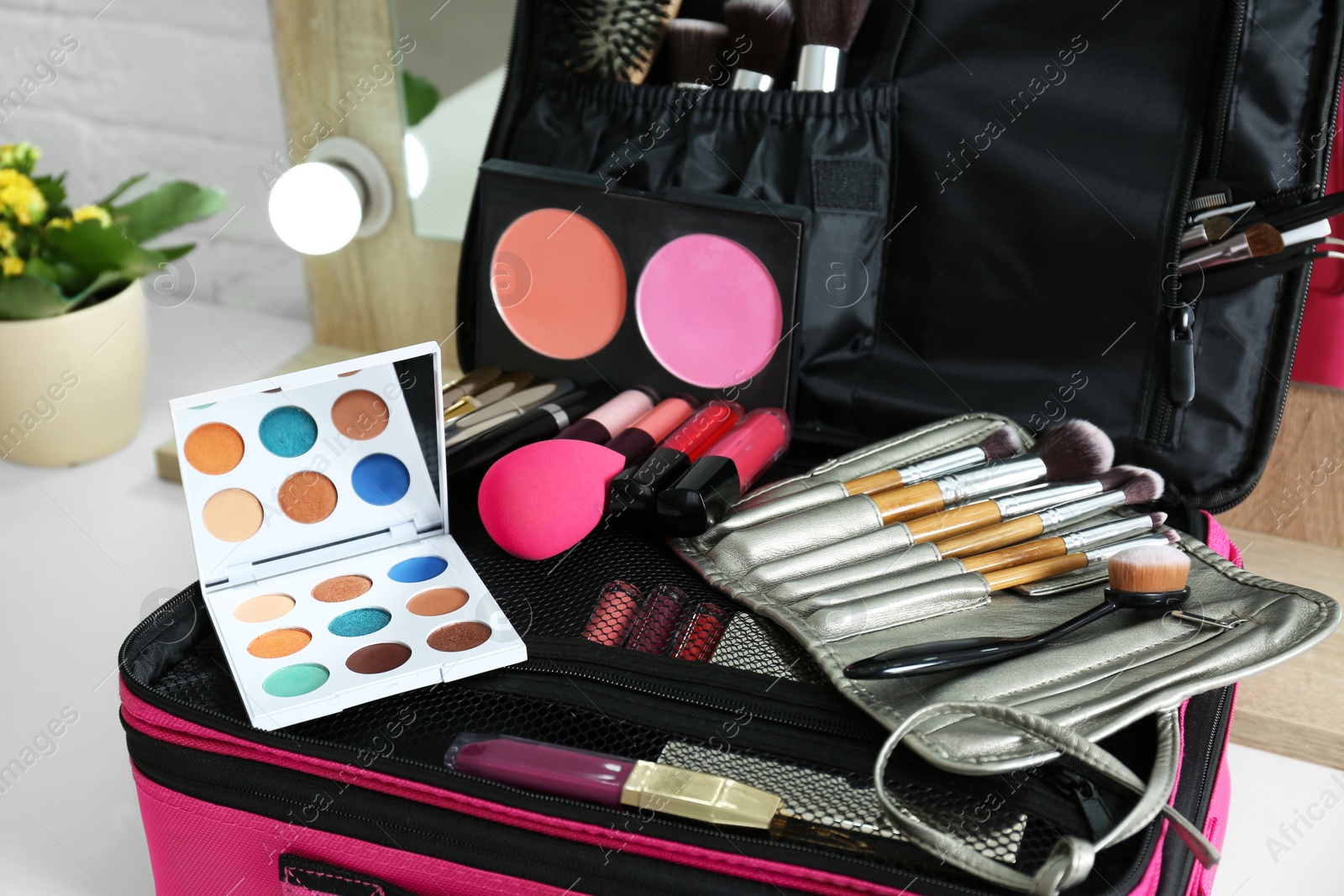 Photo of Beautician case with professional makeup products and tools on dressing table