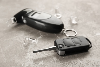 Photo of Modern breathalyzer and car key on brown marble table