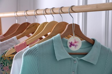 Photo of Beautiful scented wax sachet and clothes hanging on wooden rack indoors