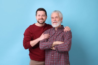 Photo of Happy son and his dad on light blue background