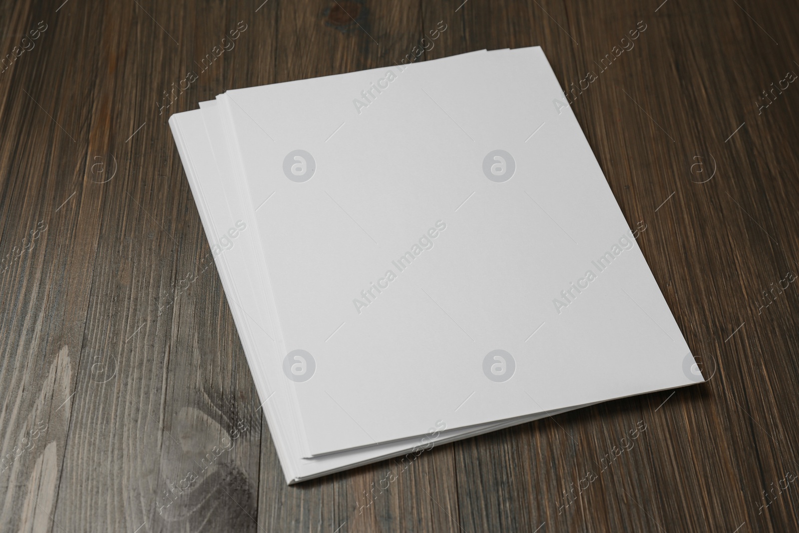 Photo of Stack of blank paper sheets on wooden table. Brochure design