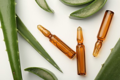 Skincare ampoules and aloe leaves on white background, flat lay