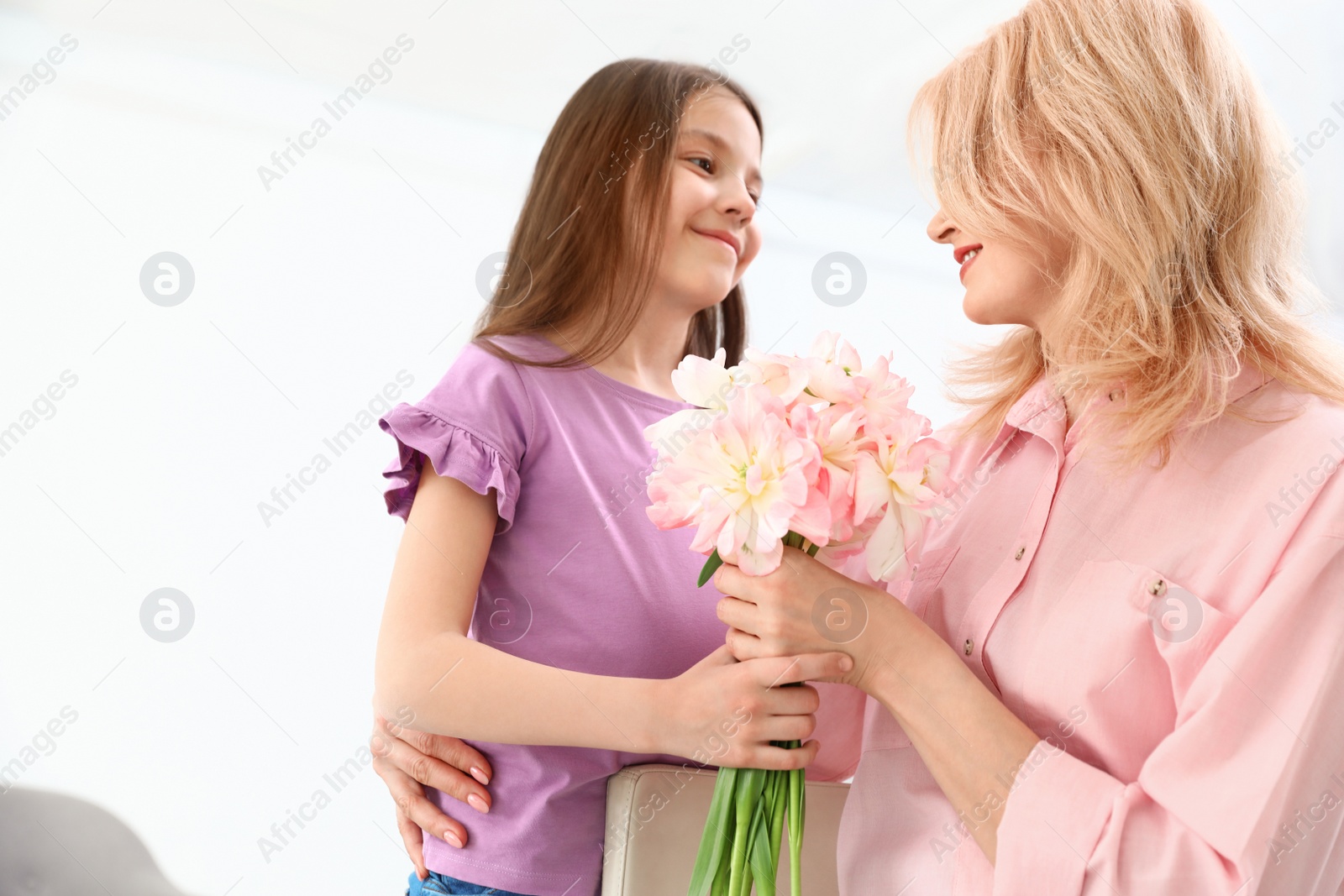 Photo of Little daughter congratulating her mature mom at home. Happy Mother's Day