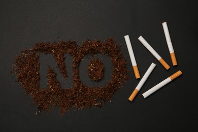 Photo of Word No made of tobacco and cigarettes on black table, flat lay. Stop smoking concept