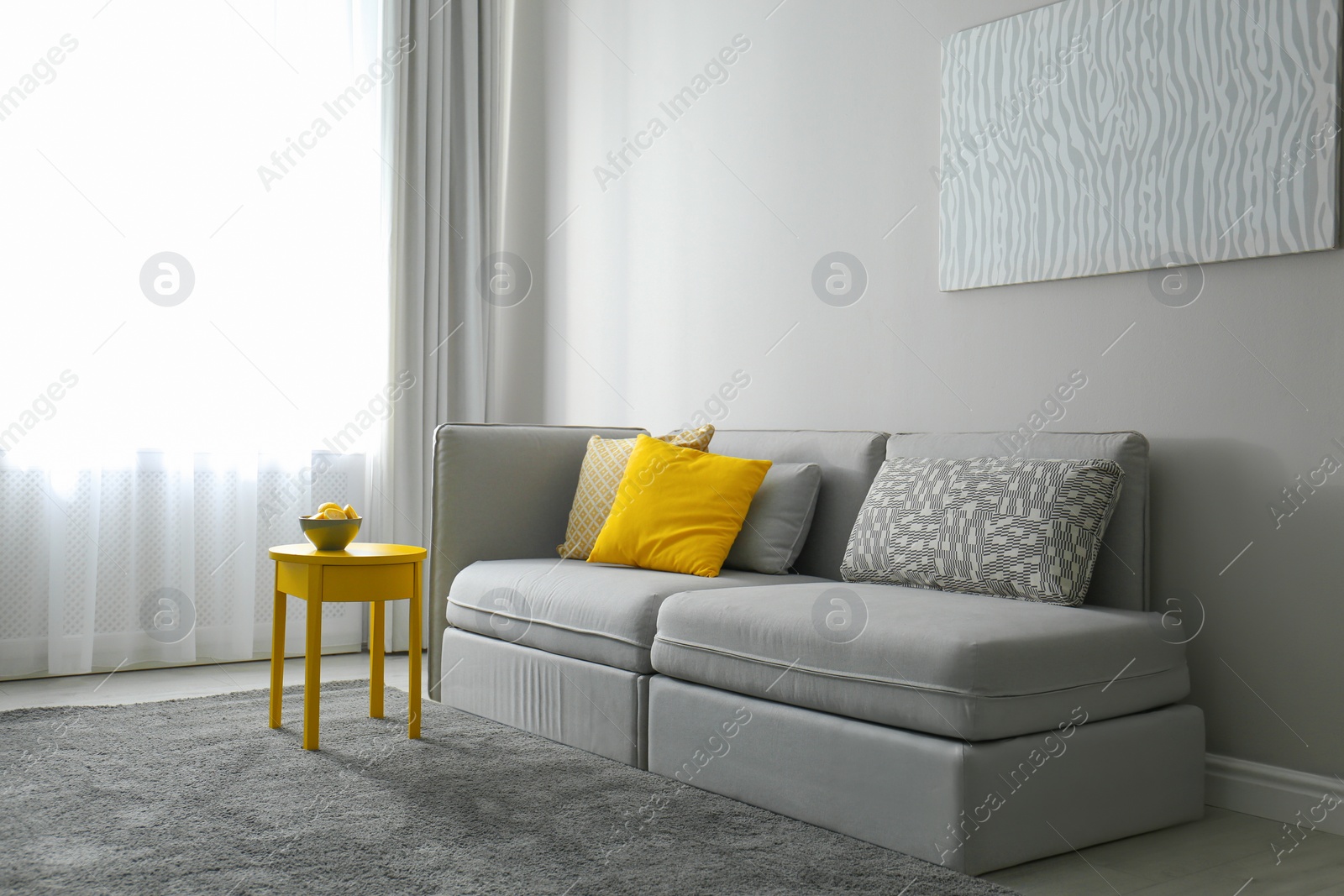 Photo of Stylish living room with sofa. Interior design in grey and yellow colors