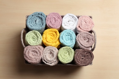 Photo of Wicker basket with clean soft towels on wooden table, top view