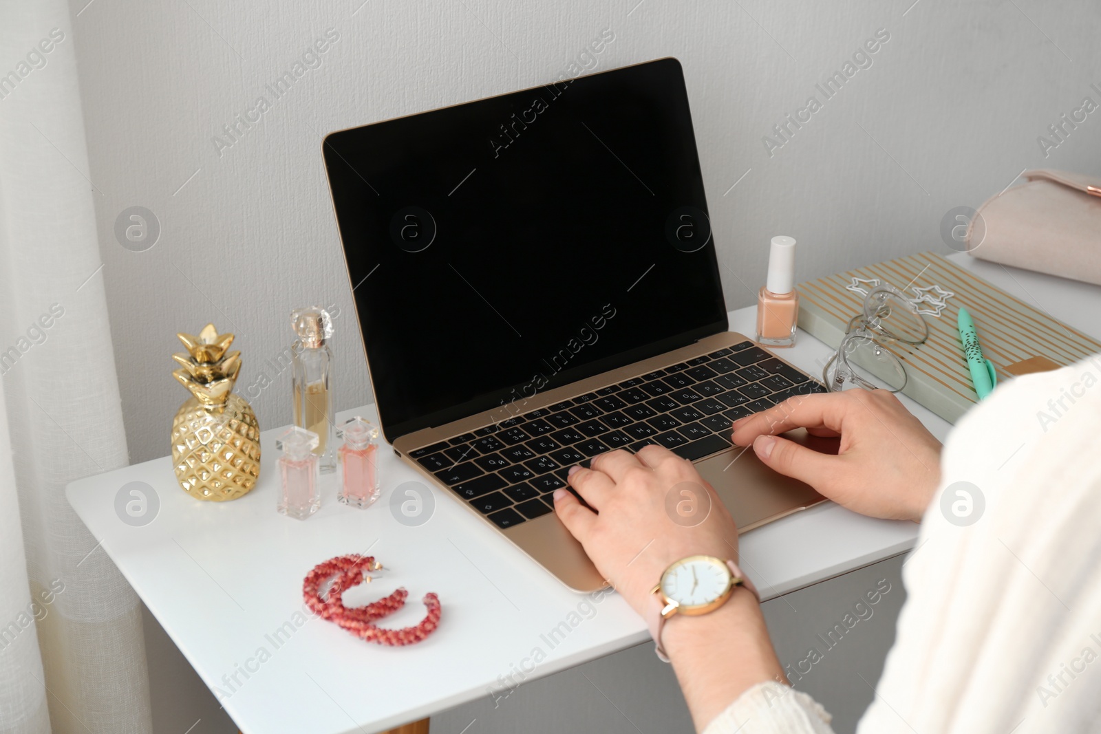 Photo of Woman with cosmetic products using laptop at table, closeup. Beauty blogger
