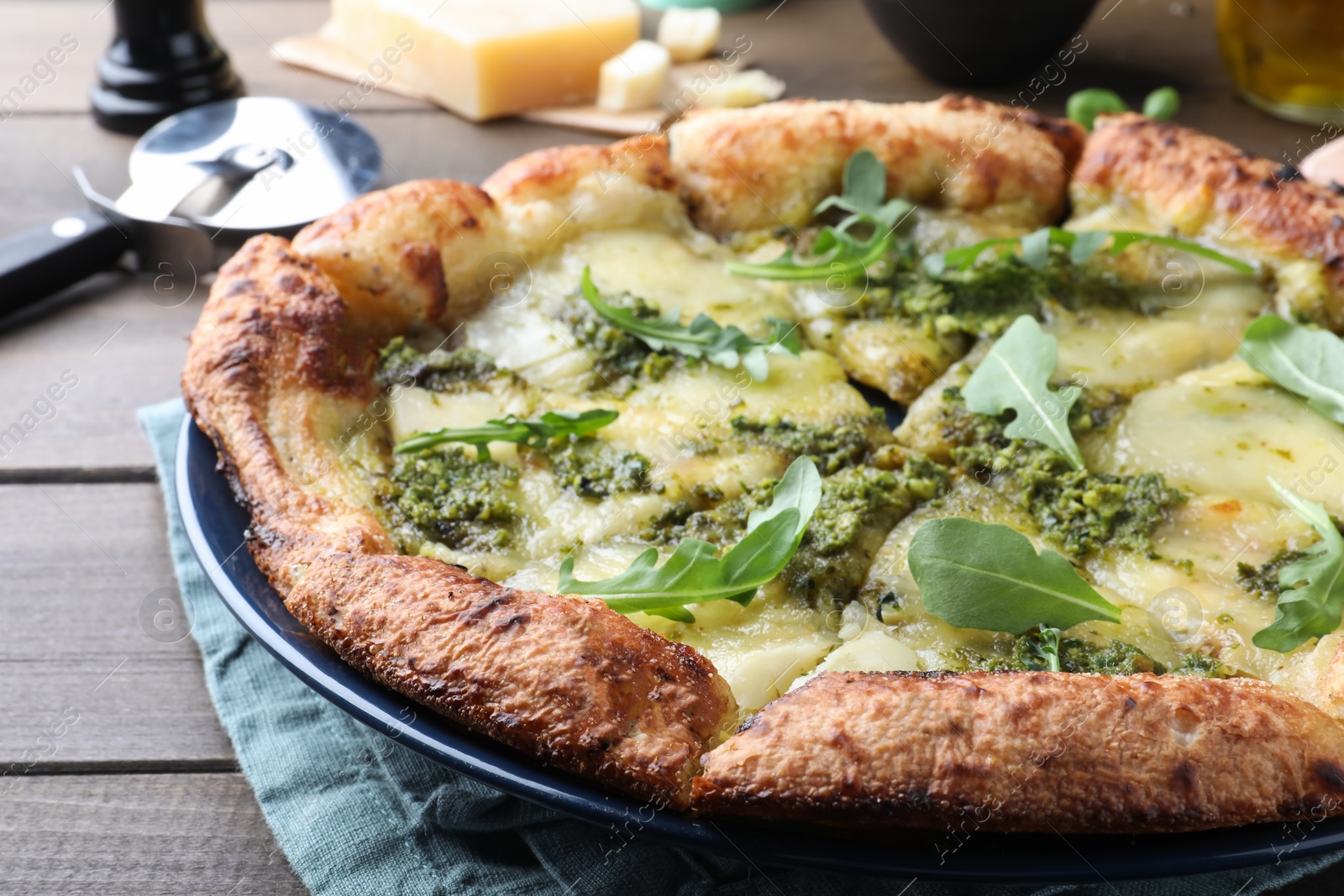 Photo of Delicious pizza with pesto, cheese and arugula on wooden table, closeup