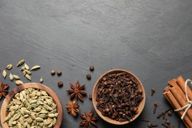 Photo of Different spices in bowls on dark gray textured table, flat lay. Space for text