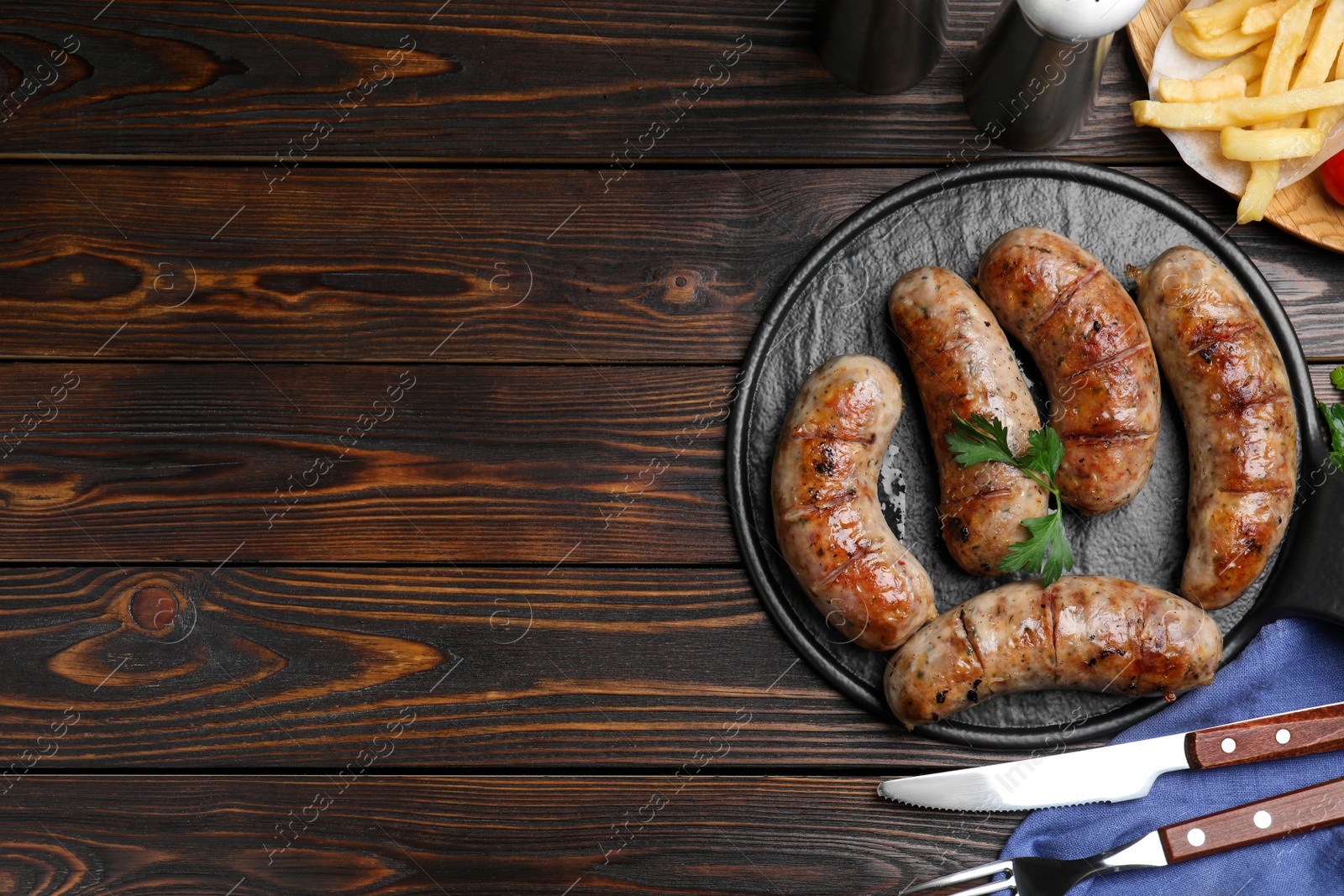 Photo of Tasty grilled sausages served on wooden table, flat lay. Space for text